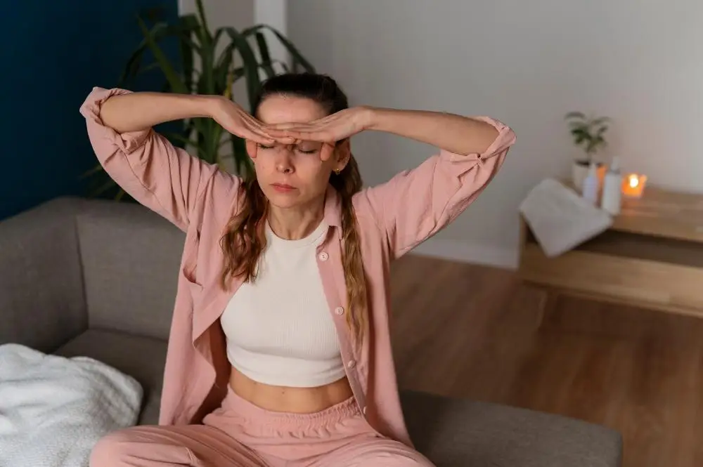 kobieta siedzi na kanapie i zaslania oczy rekami, objawy przebodzcowania w adhd