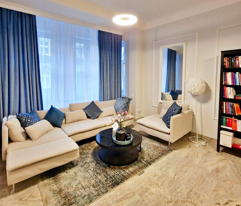 wnętrze gabinetu psychologicznego z jasną sofą, fotelem i biblioteczką – przestrzeń wsparcia psychologicznego