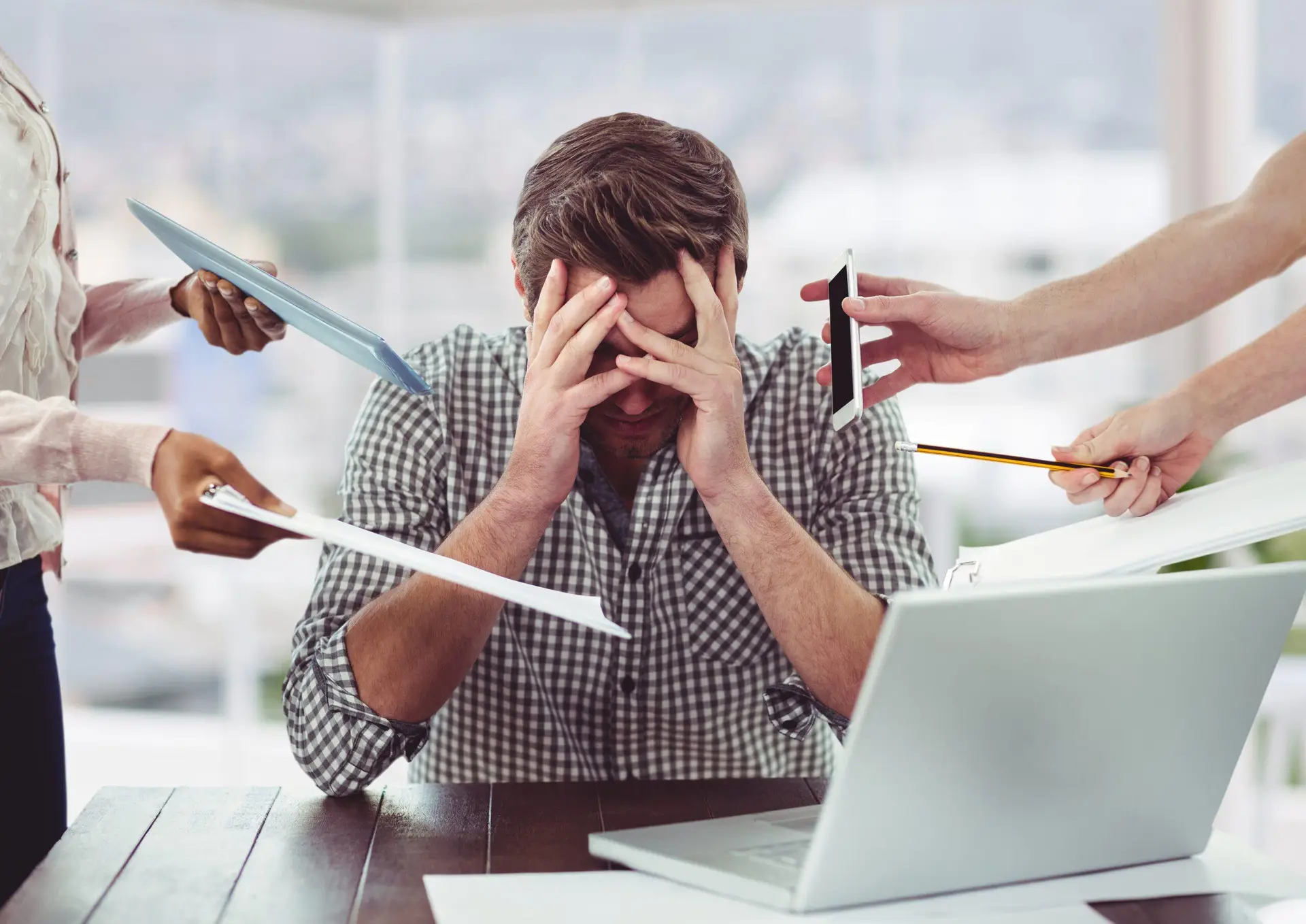 mężczyzna przeciążony nadmiarem bodźców przy biurku z laptopem – stres i trudności z koncentracją w ADHD