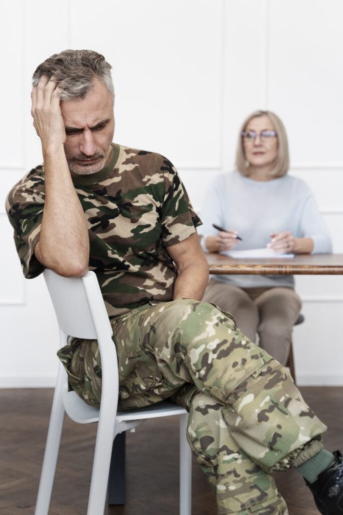 Mężczyzna w wojskowym stroju siedzący na terapii u psychologa – objawy PTSD i trauma po doświadczeniach wojennych