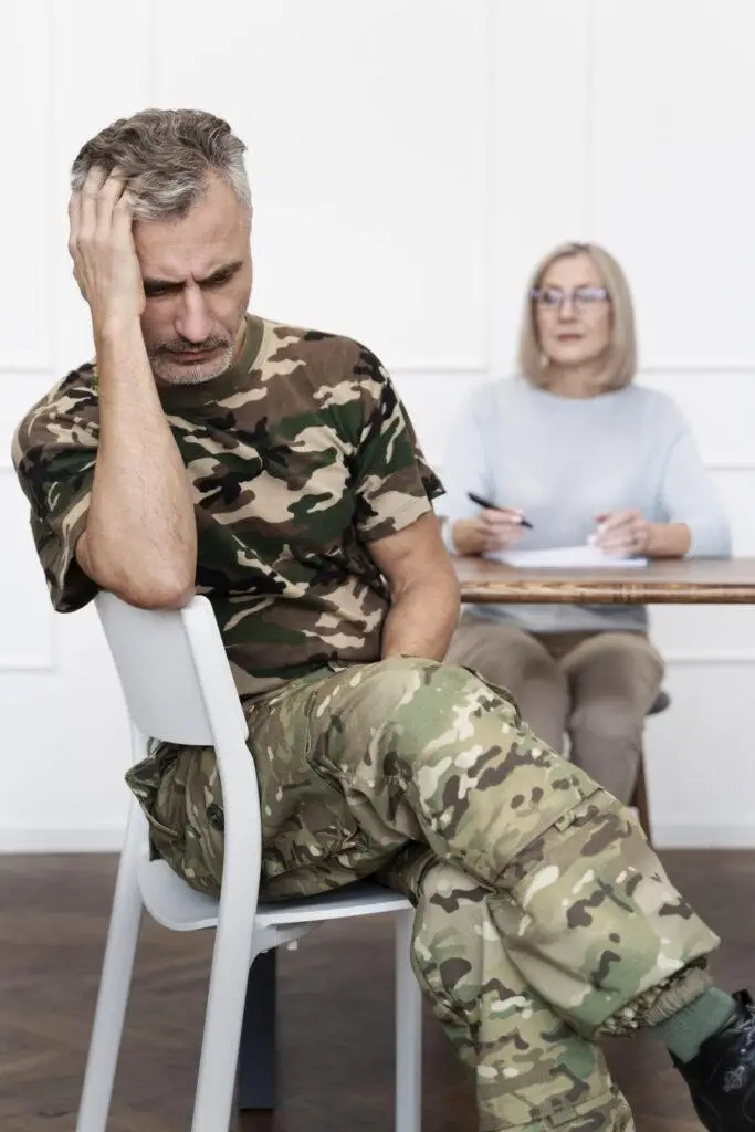 Mężczyzna w wojskowym stroju siedzący na terapii u psychologa – objawy PTSD i trauma po doświadczeniach wojennych