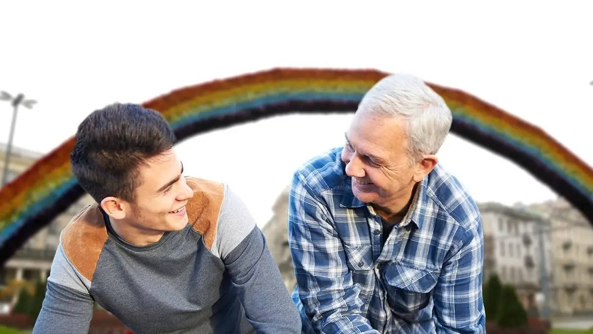 Dwoch mezczyzn rozmawiajacych na tle teczy – wsparcie psychologiczne LGBT