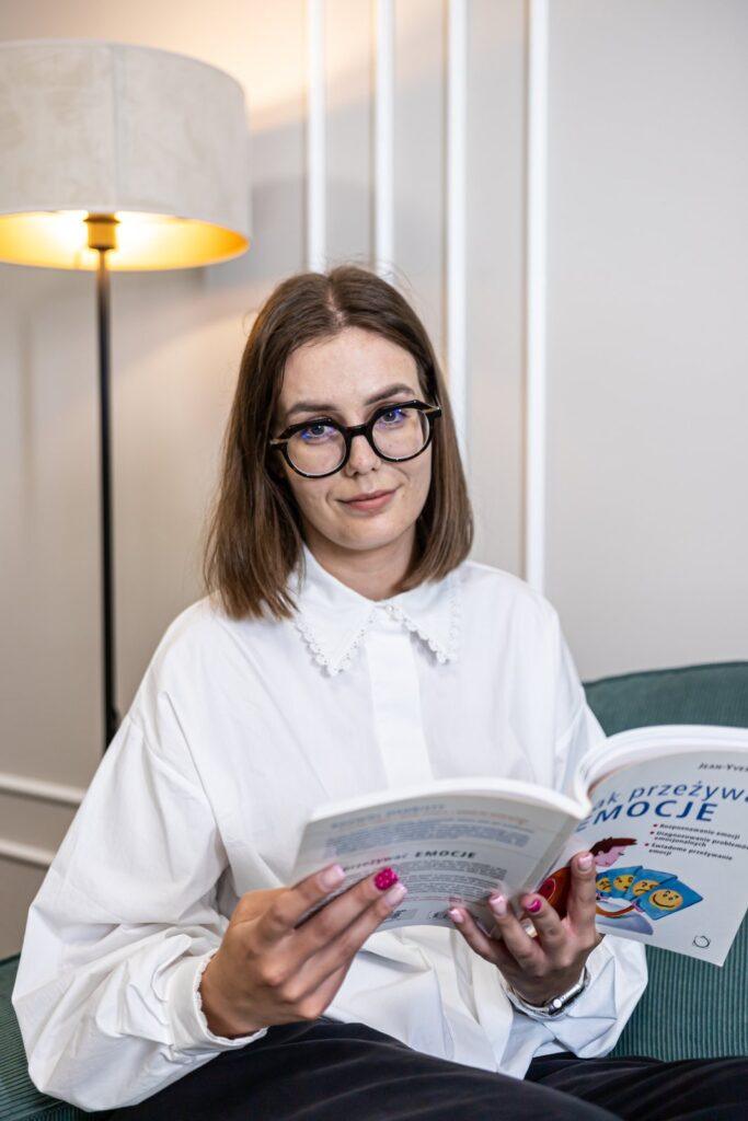 Aleksandra Pomagier – psycholog Centrum Optimus w Poznaniu, czytająca książkę w gabinecie