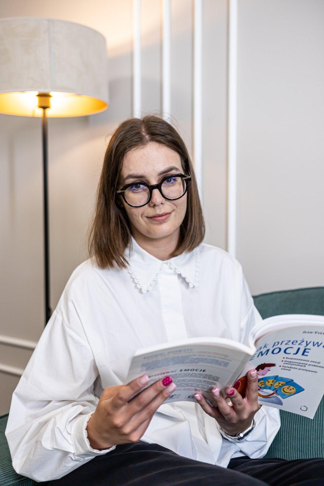 Aleksandra Pomagier – psycholog Centrum Optimus w Poznaniu, czytająca książkę w gabinecie